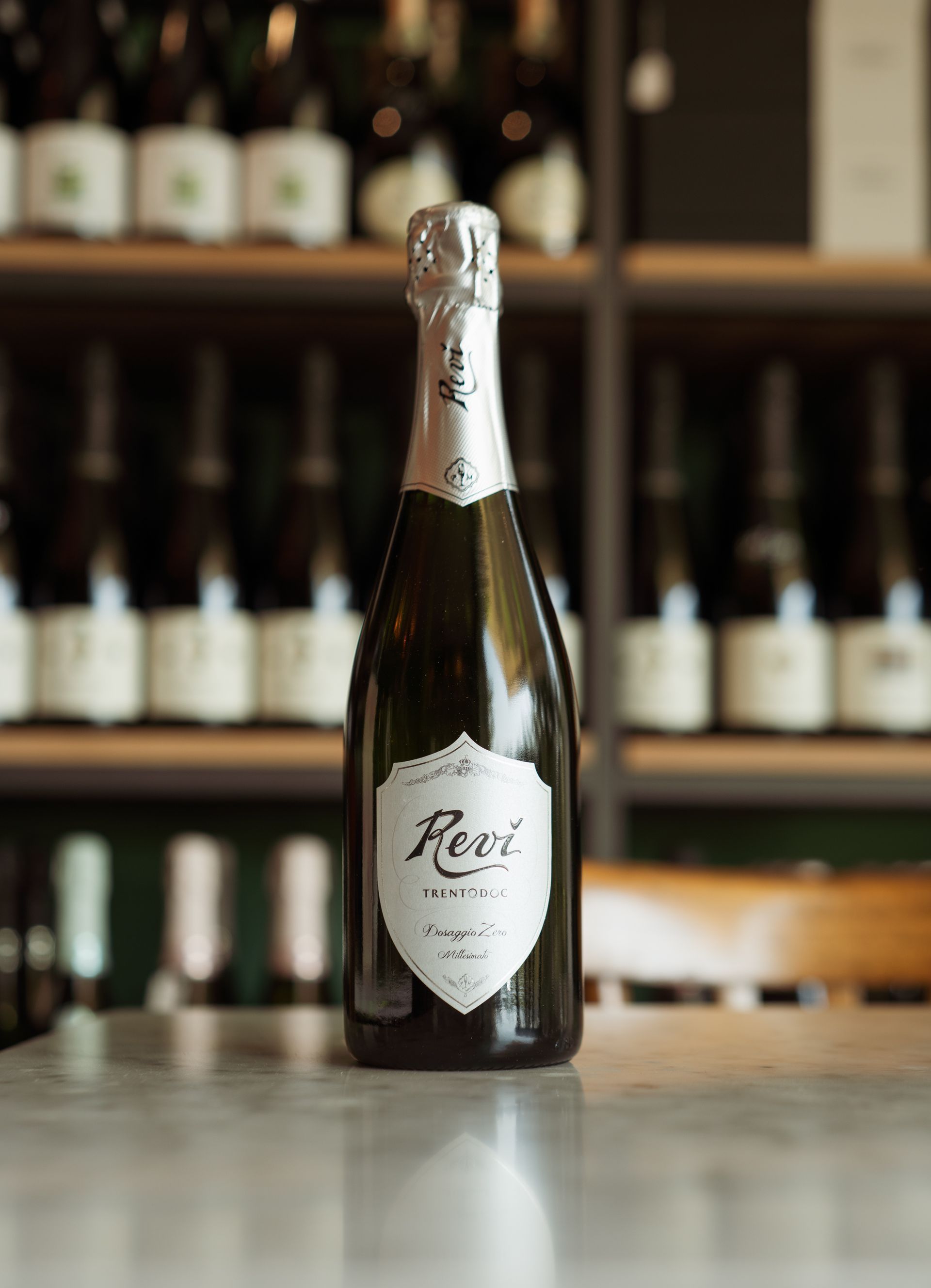 Una bottiglia di vino è appoggiata su un tavolo davanti a uno scaffale.