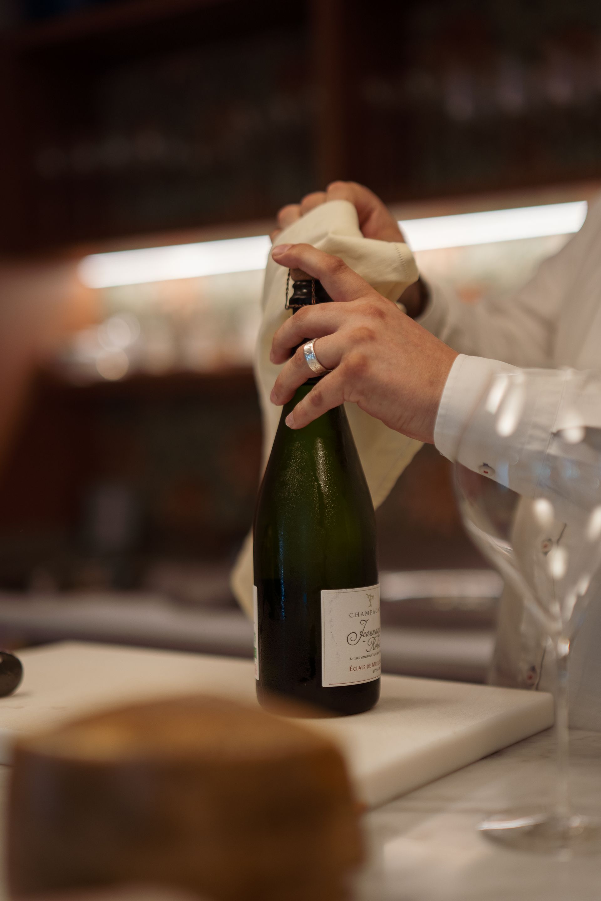 Una persona sta aprendo una bottiglia di champagne con un tovagliolo.