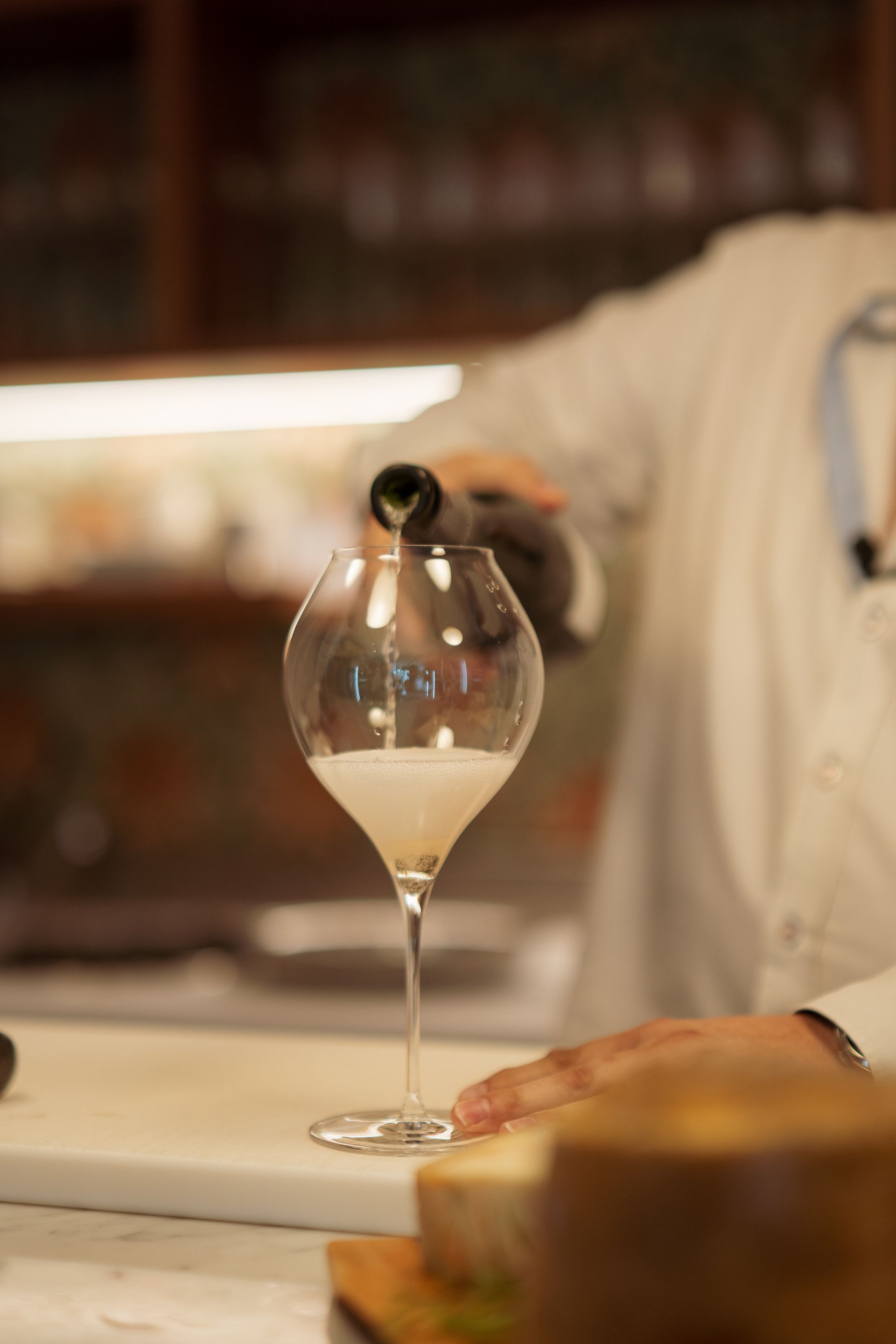 Una persona sta versando del vino in un bicchiere su un tavolo.