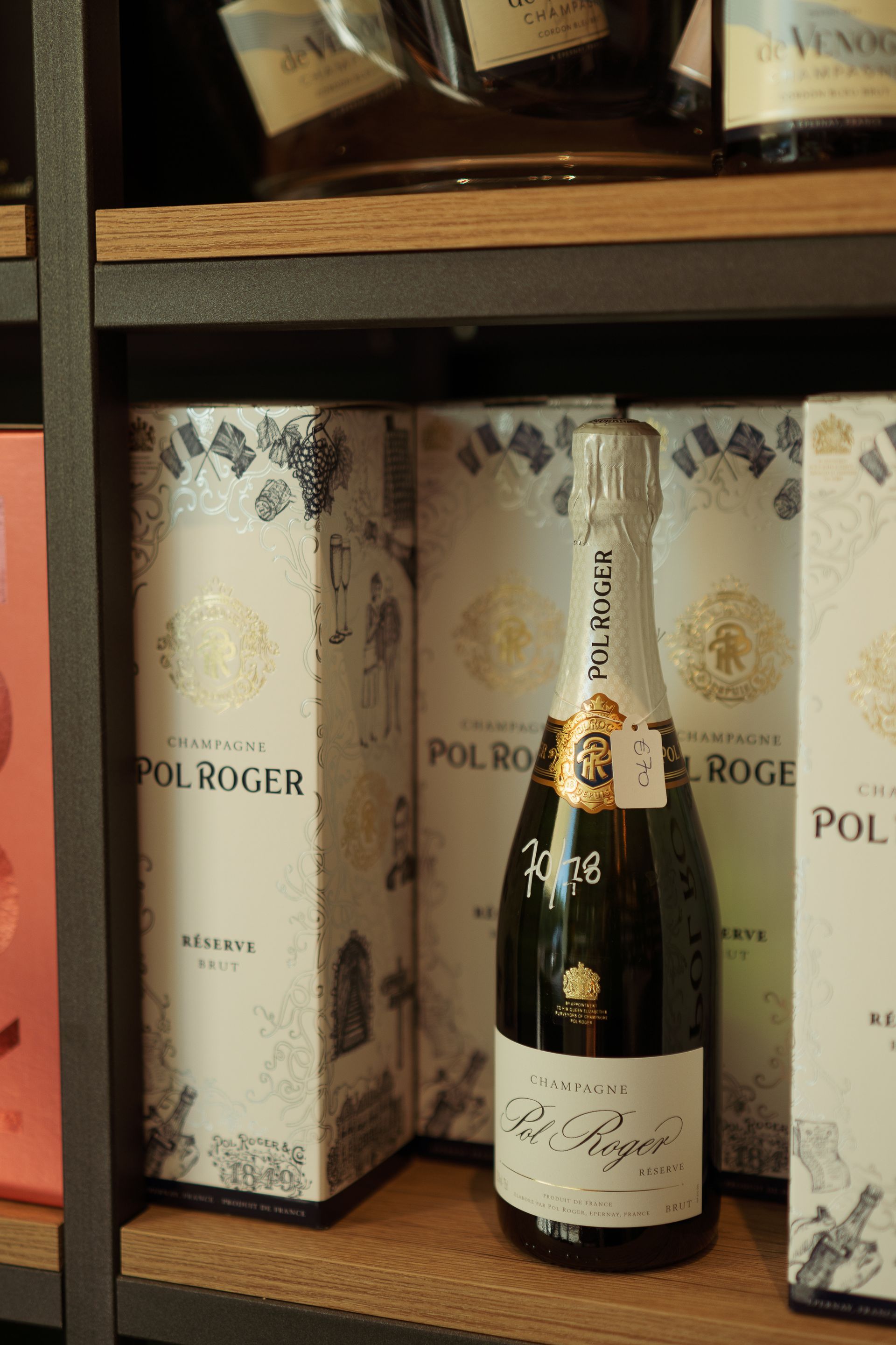 Una bottiglia di champagne Pol Roger è appoggiata su uno scaffale di legno.