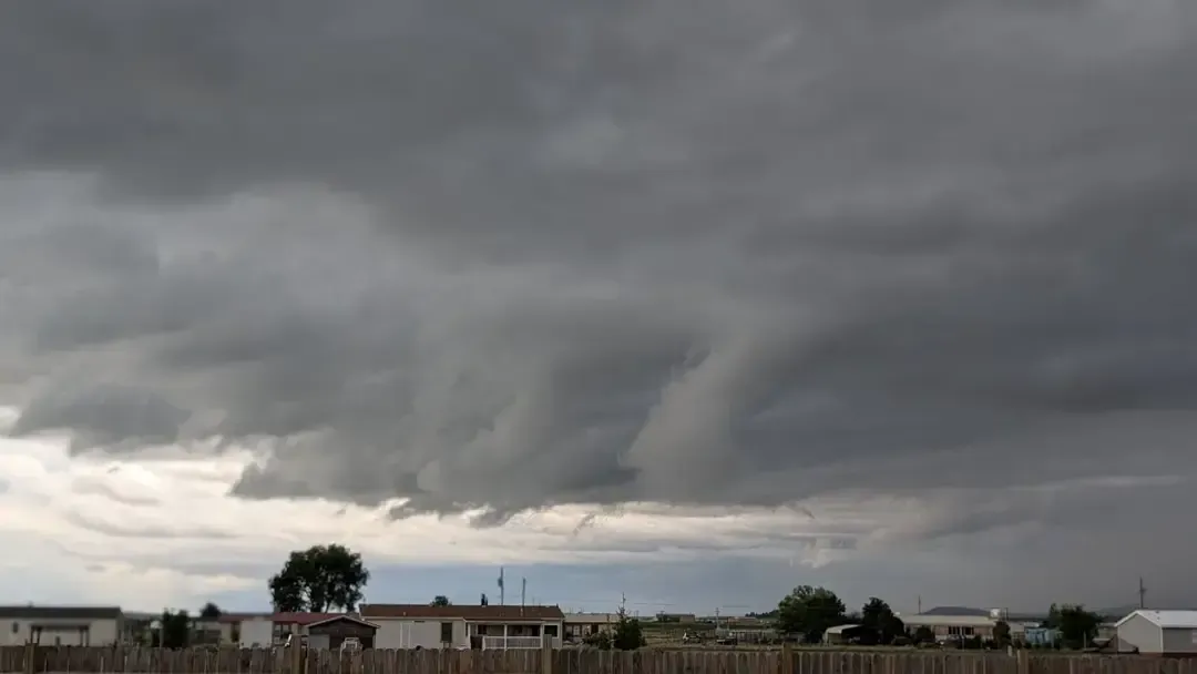 Dark, stormy clouds hanging low over a suburban landscape. Gray sky and ominous weather.