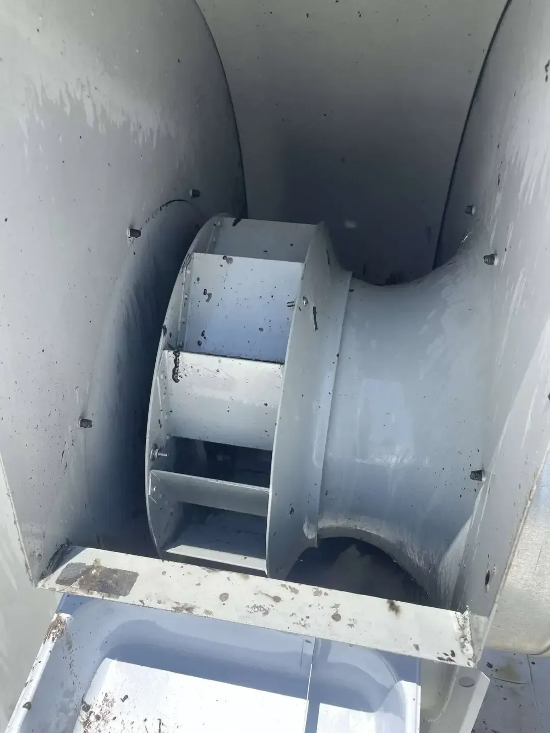 Inside view of a metallic industrial fan, showing the impeller with blades and the housing. Grey color.