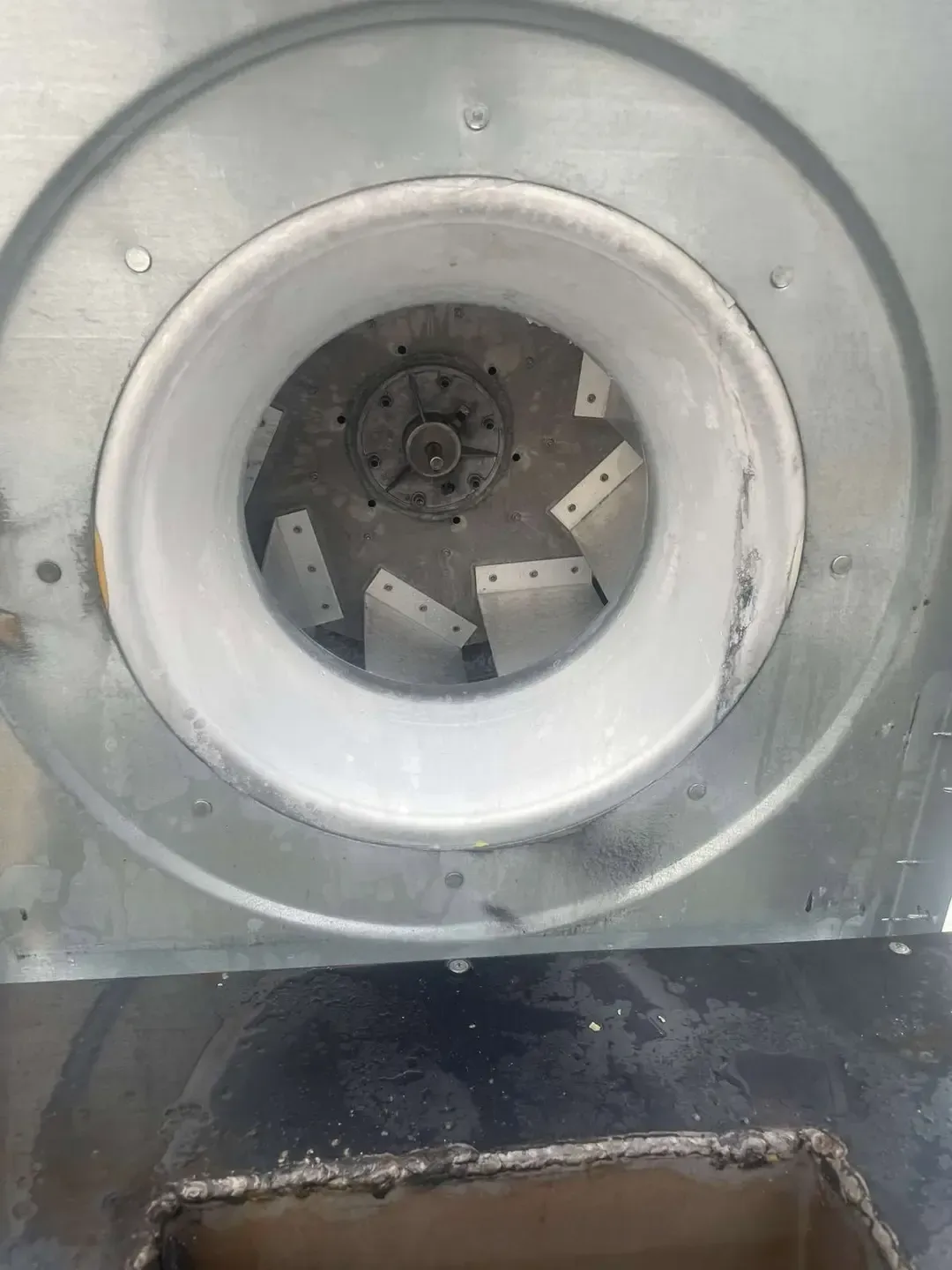 An open, circular blower fan with a metal housing and white interior, visible blades, and a central hub.