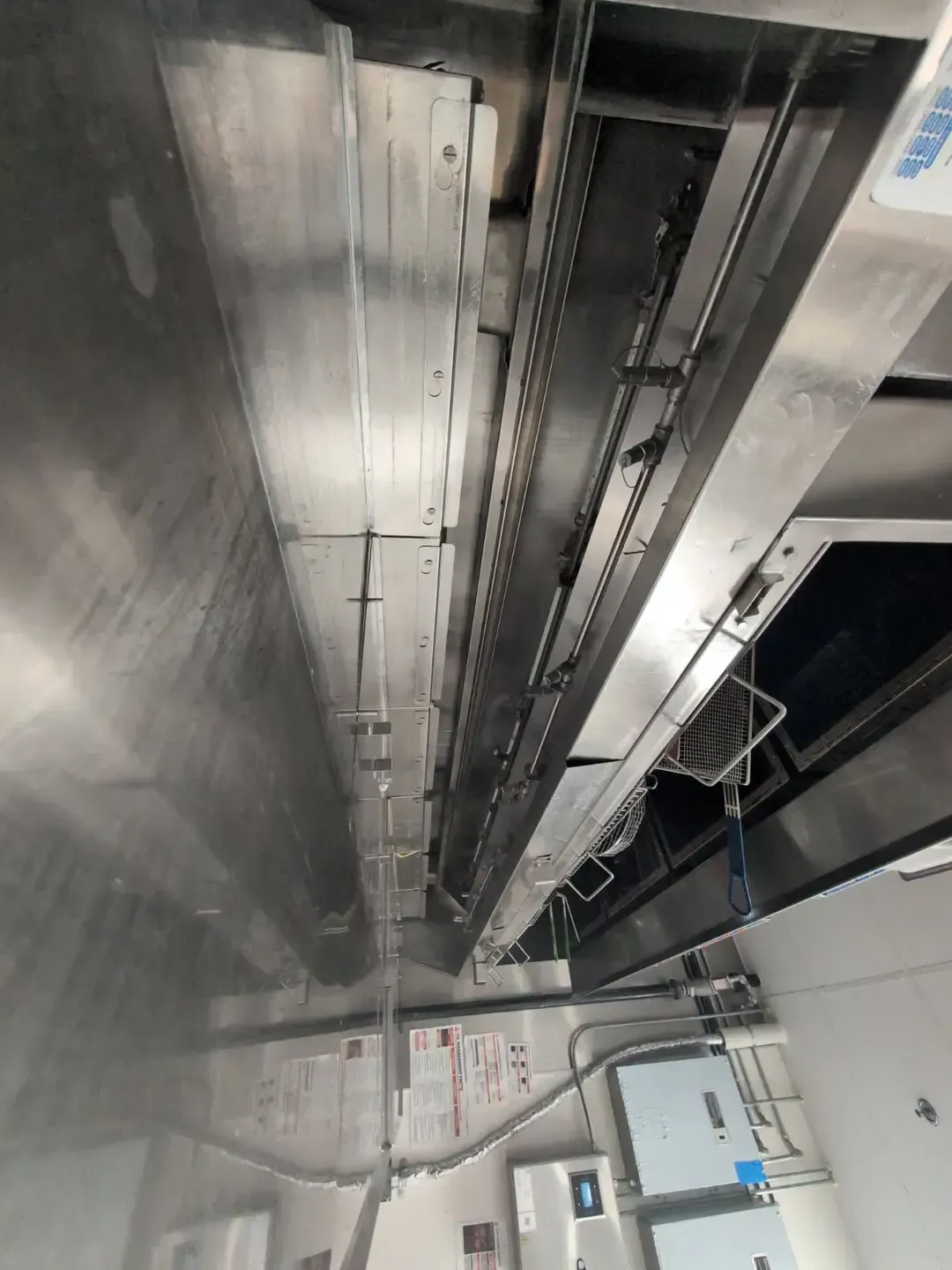Stainless steel elevator interior, showing a chain mechanism, various panels, and a control panel.