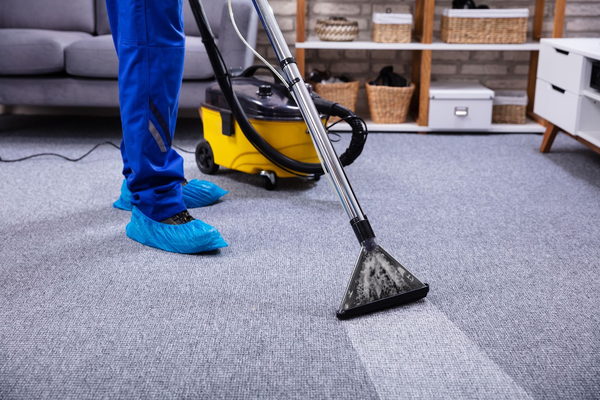 A person is using a vacuum cleaner to clean a carpet in a living room.