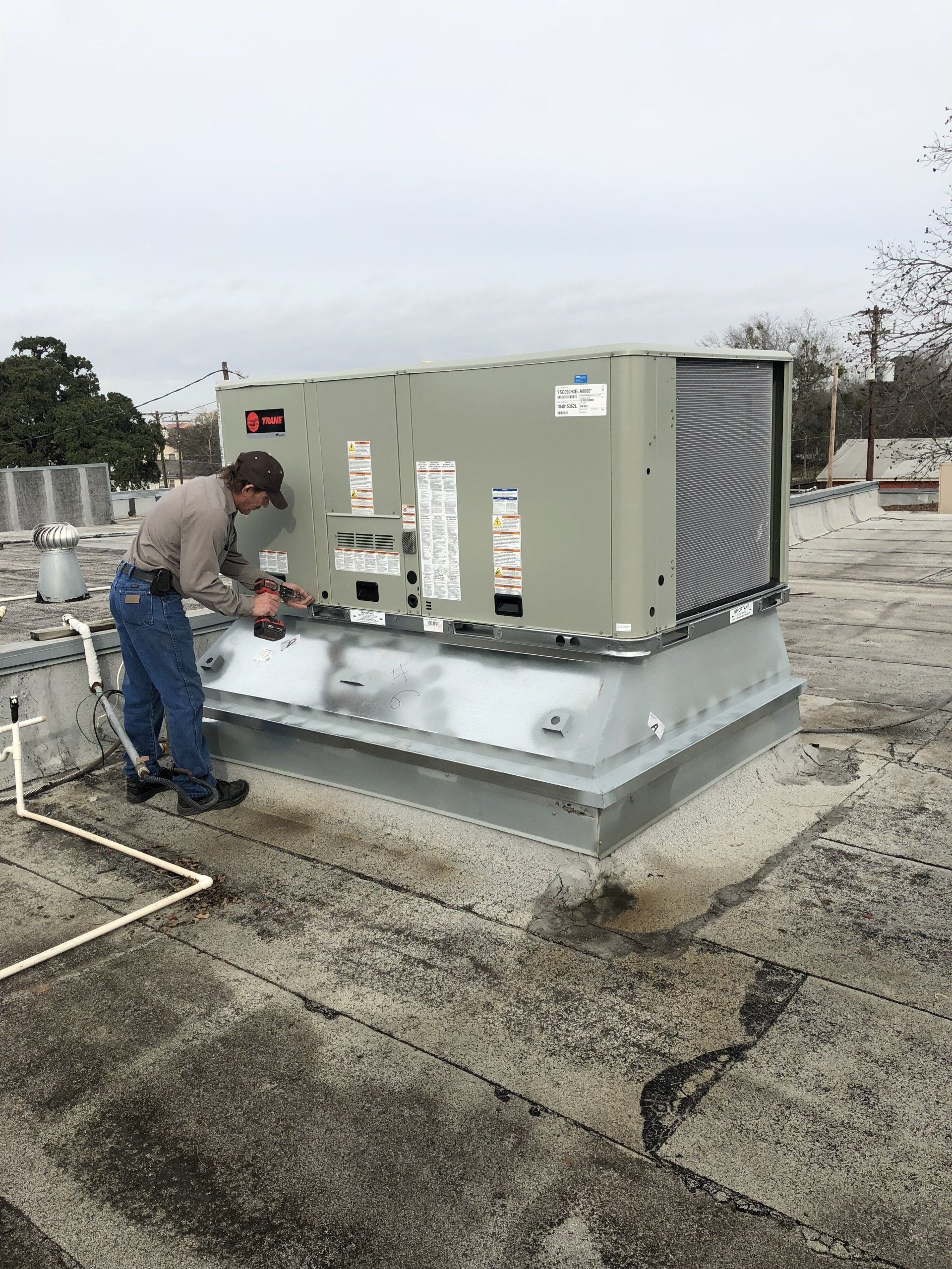 Man Using Electric Drill On The HVAC Unit — San Antonio, TX — P-C Air & Refrigeration