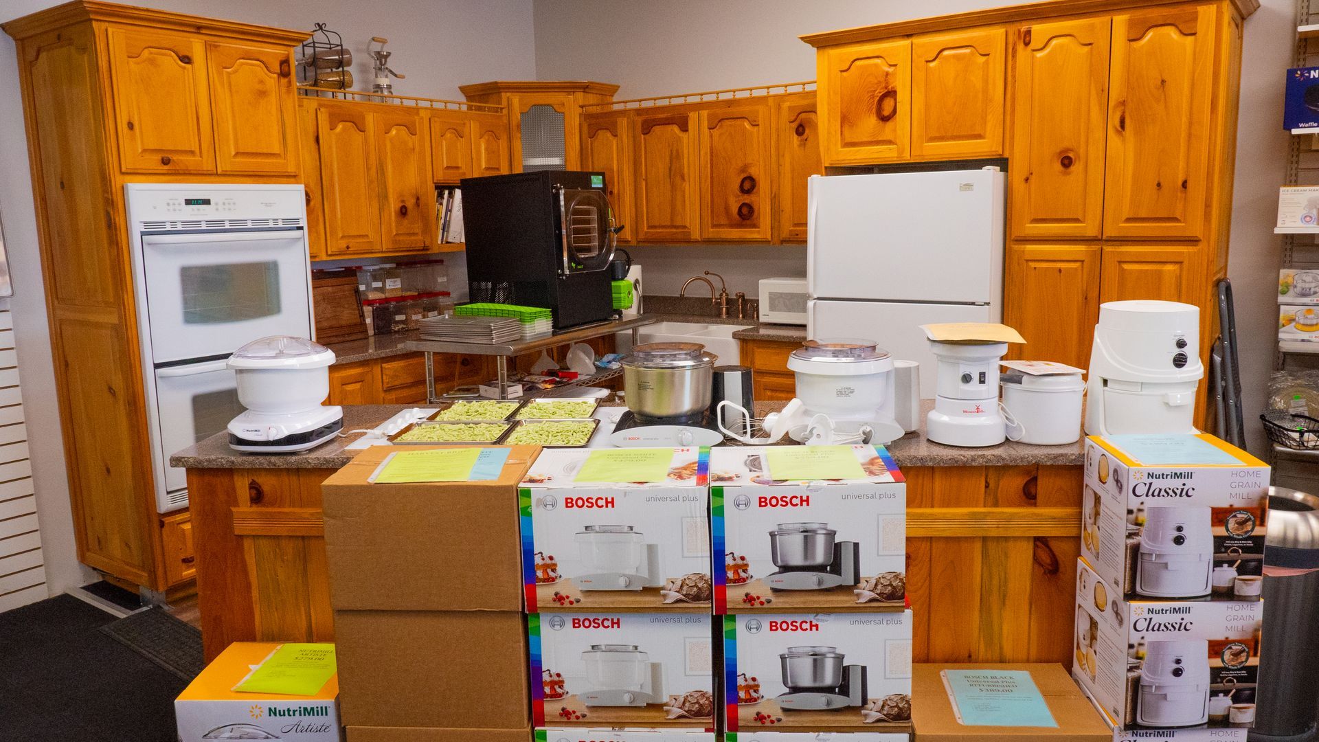 A kitchen display with wooden cabinets and a variety of kitchen appliances on countertops and in boxes.