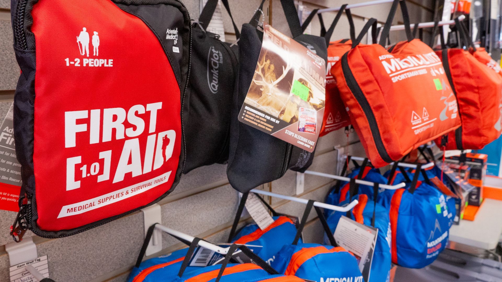 Close-up of first aid kits of varying sizes and colors hanging on display at a store.