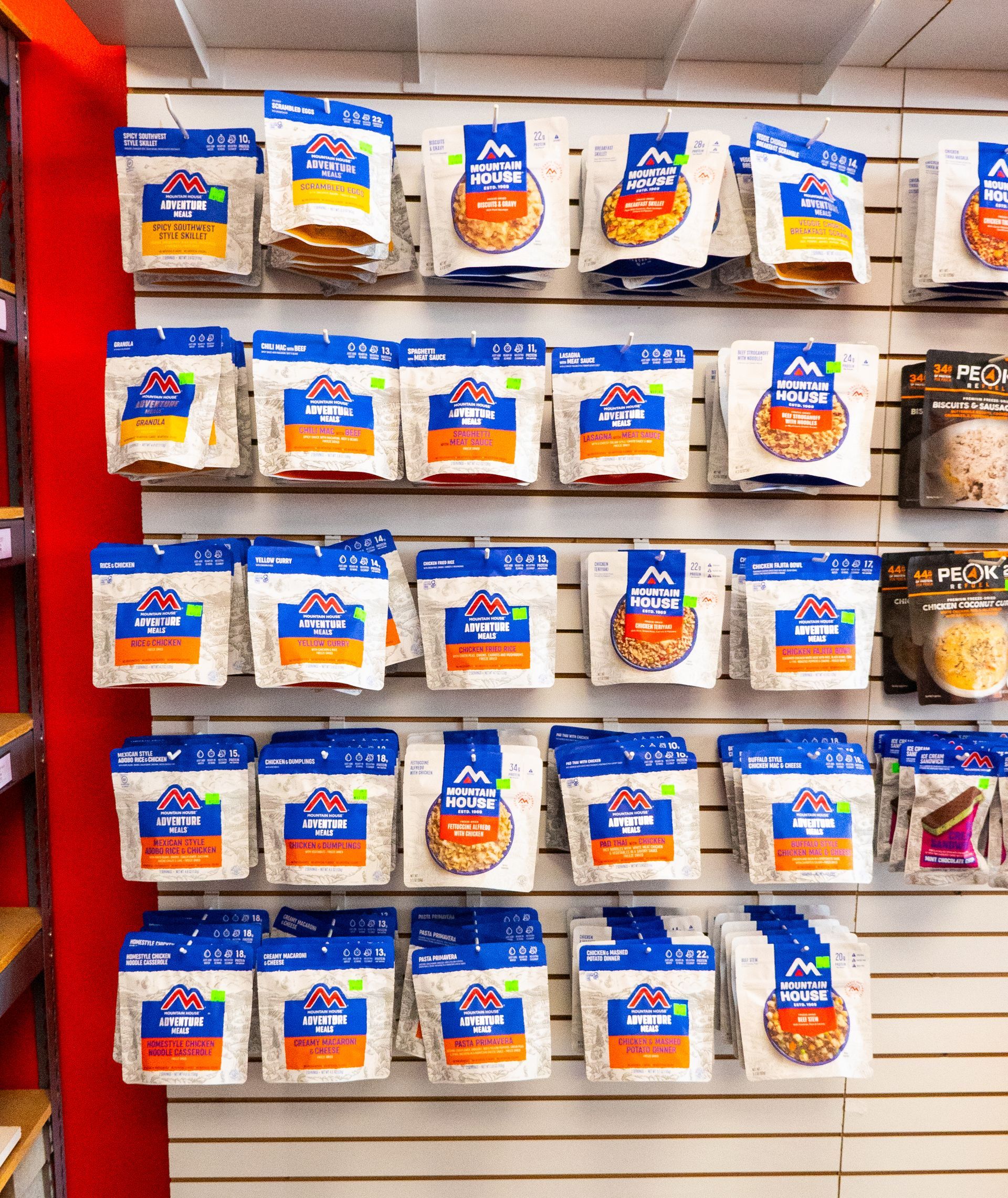 Bags of freeze-dried food displayed on shelves in a store. The bags are white with blue and orange labels.