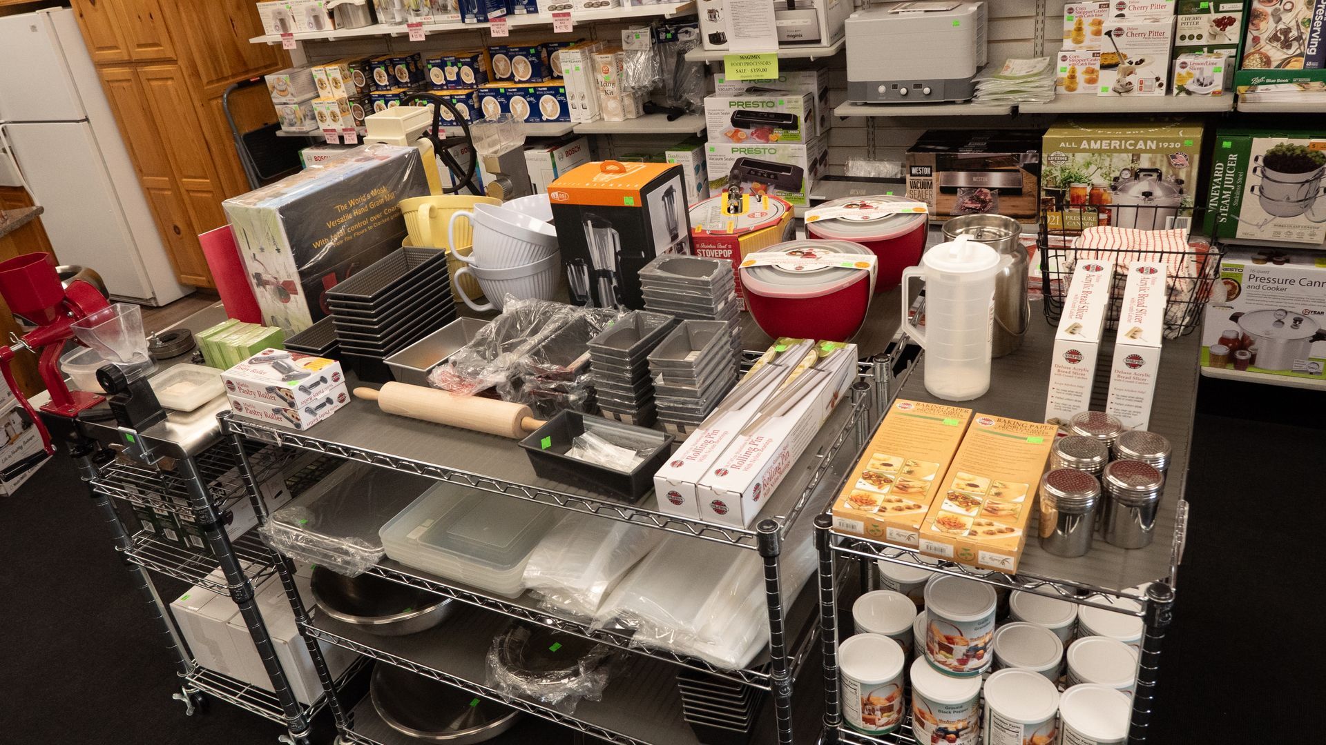 Shelves stocked with various kitchen utensils and appliances in a store, including baking pans, mixers, and coffee makers.