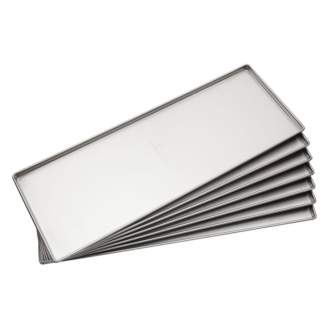 Stack of rectangular, stainless steel tart pans with scalloped edges.
