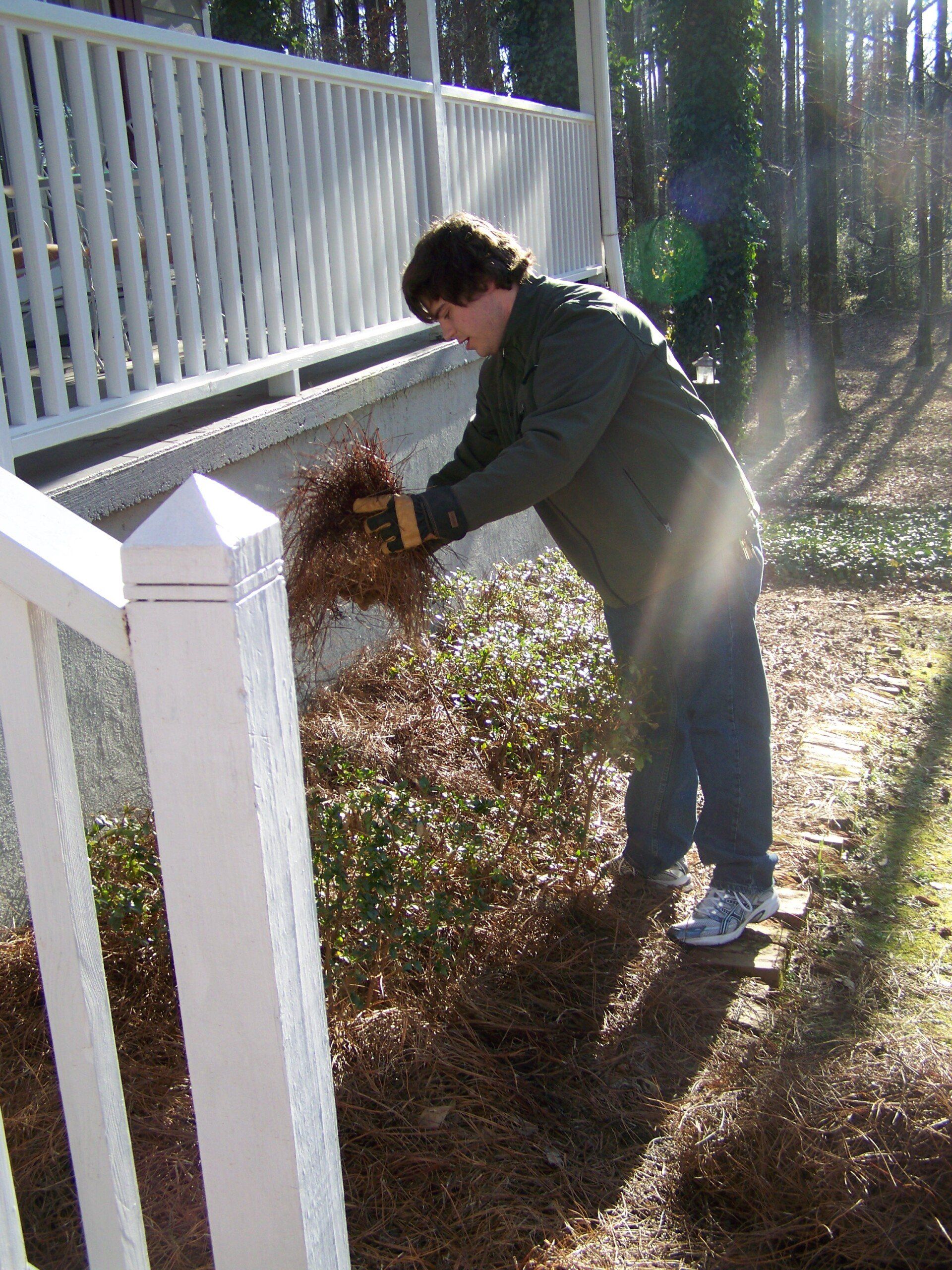 A man standing next to a white railing holding a shovel