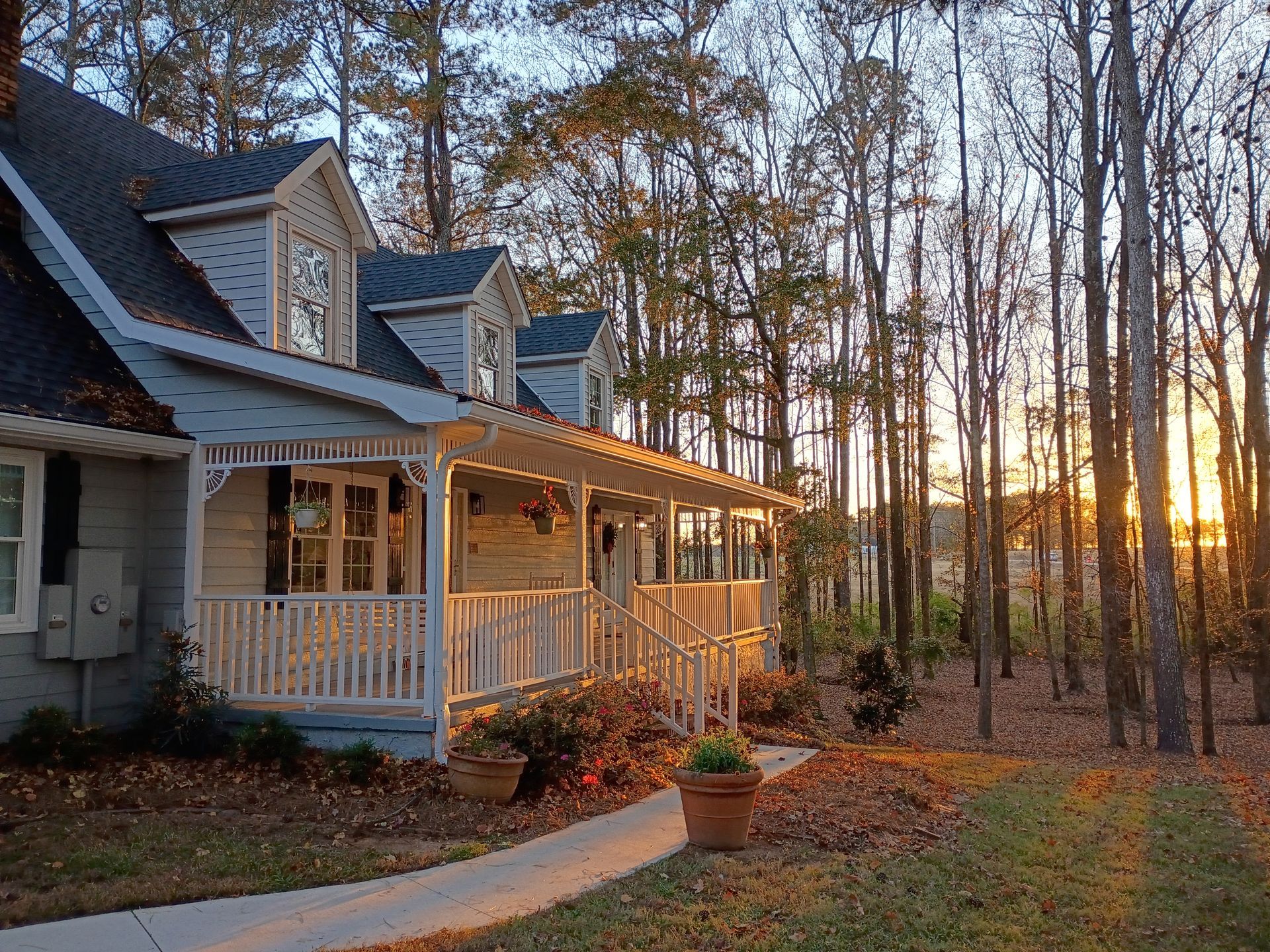 A white house with a handicap ramp is surrounded by trees.