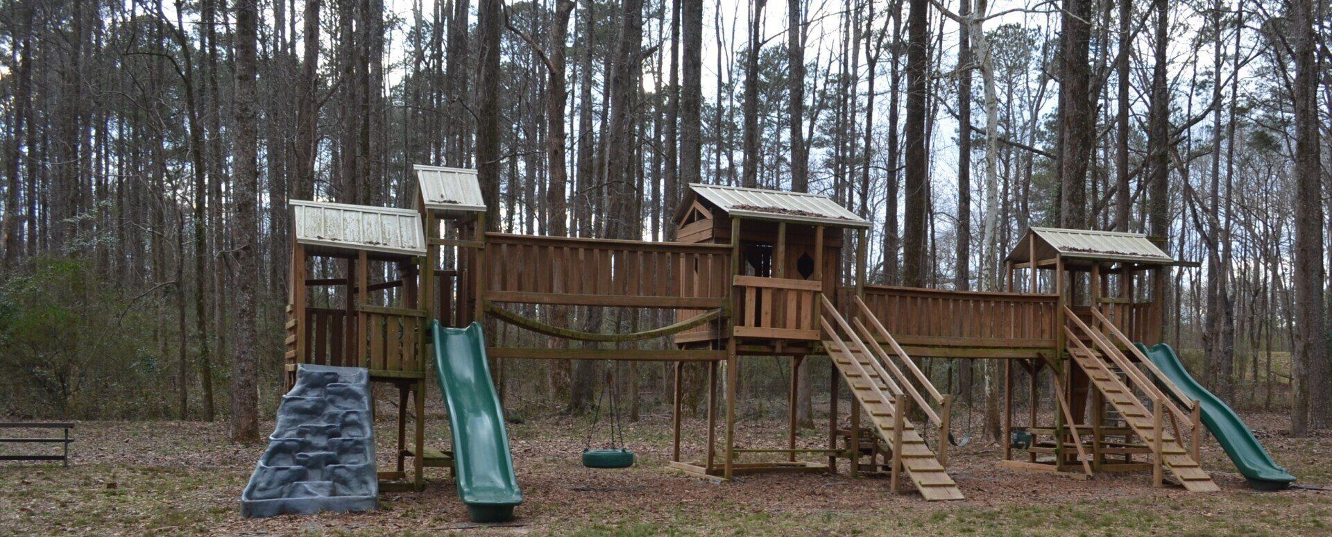 A wooden playground set in the middle of a forest