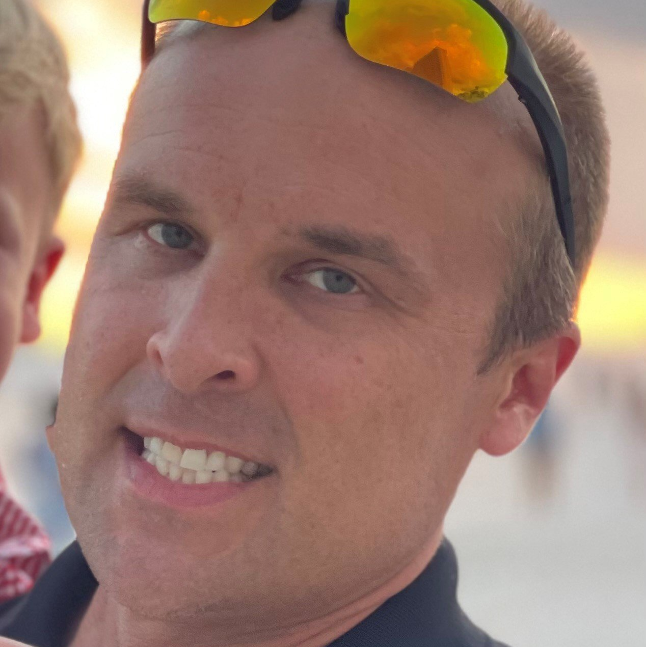 A man wearing sunglasses is smiling for the camera