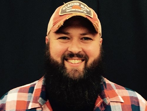 A man with a beard wearing a hat that says glacier bay