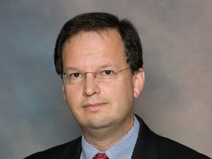 A man in a suit and tie is looking at the camera.