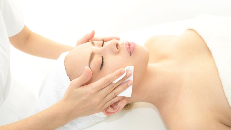 Un'estetista pulisce delicatamente il viso di una donna