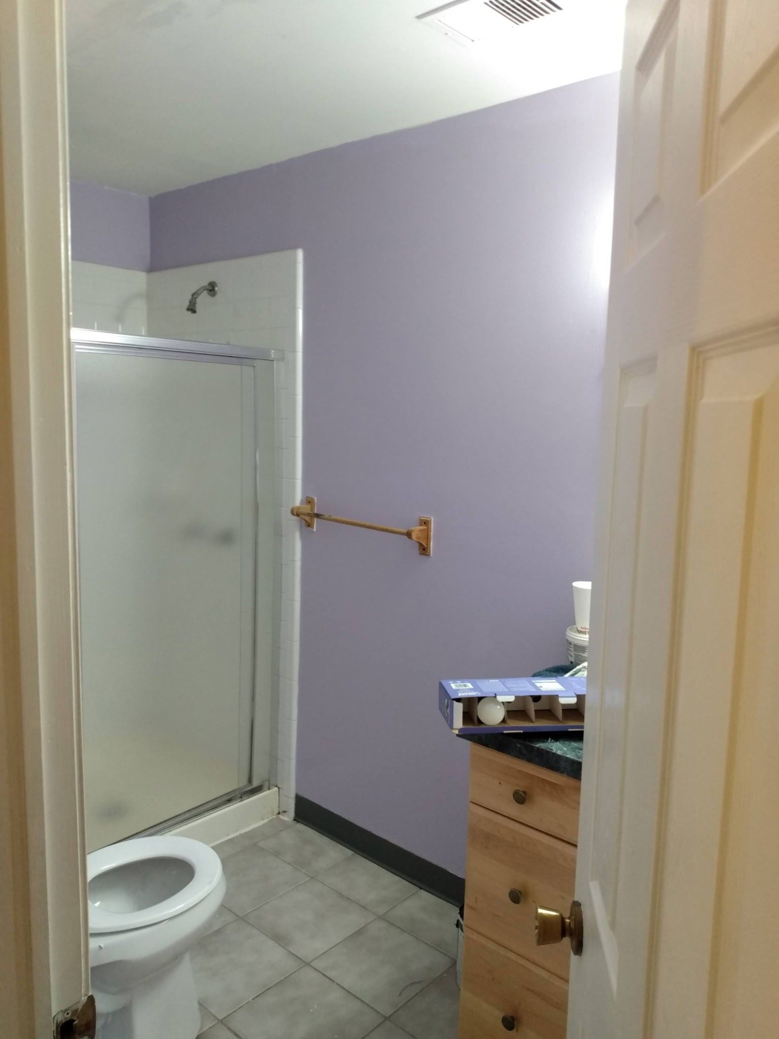 A bathroom with a toilet , sink , shower and purple walls.