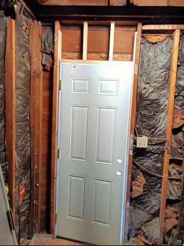 A metal door is being installed into a wooden wall.