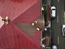 An aerial view of a red roof with people working on it.