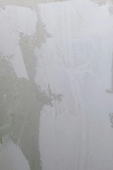 A reflection of a person in a puddle of water on a white surface.