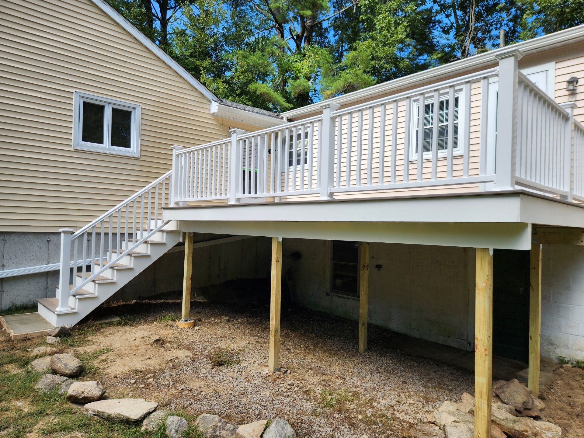 A white deck with stairs leading up to it is in front of a house.