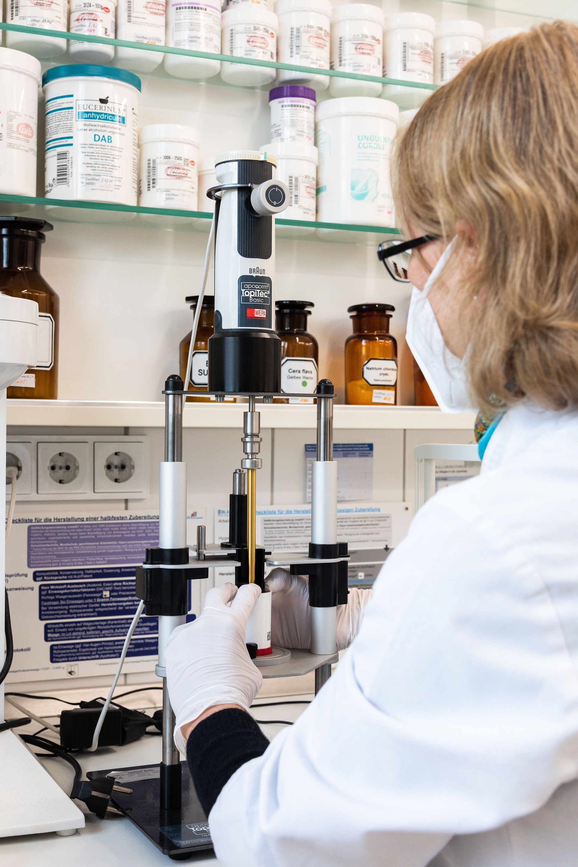 Eine Frau im Laborkittel arbeitet an einer Maschine.