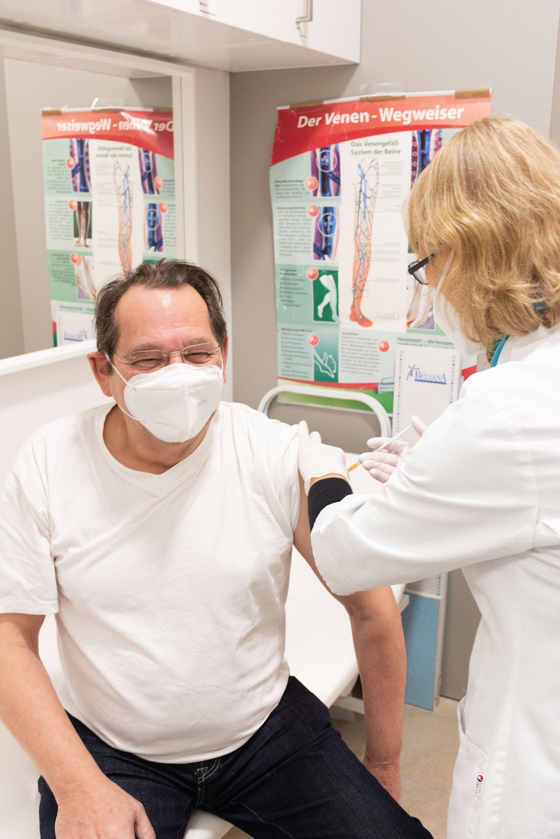 Ein Mann mit einer Maske wird von einem Arzt geimpft.