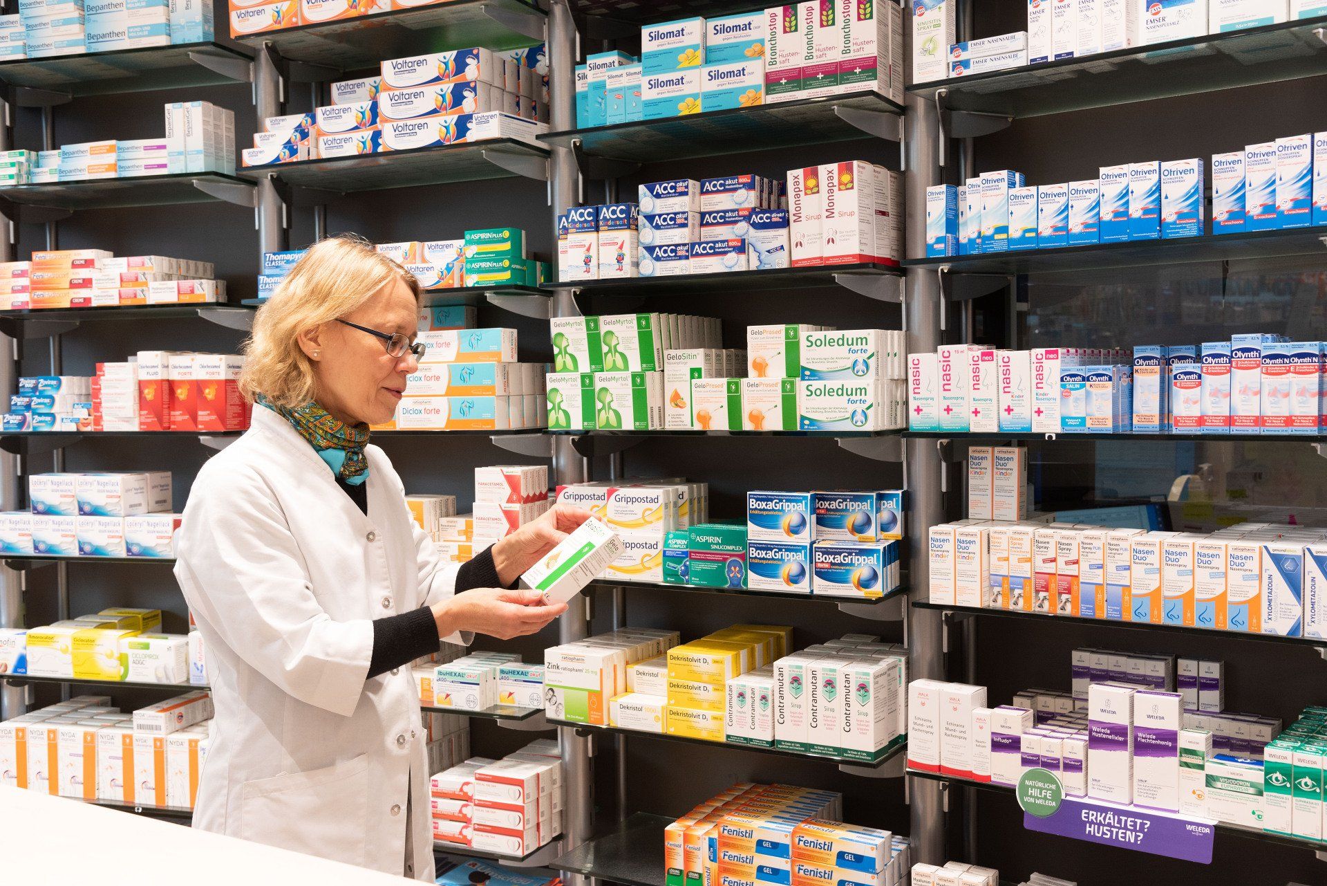 Eine Apothekerin betrachtet in einer Apotheke eine Medikamentenflasche.