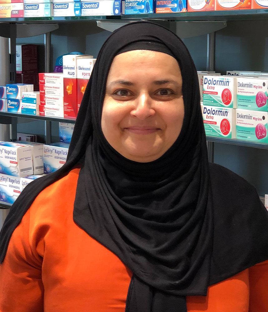 Eine Frau mit schwarzem Hijab steht vor einem Regal mit Dolormut-Boxen darauf.