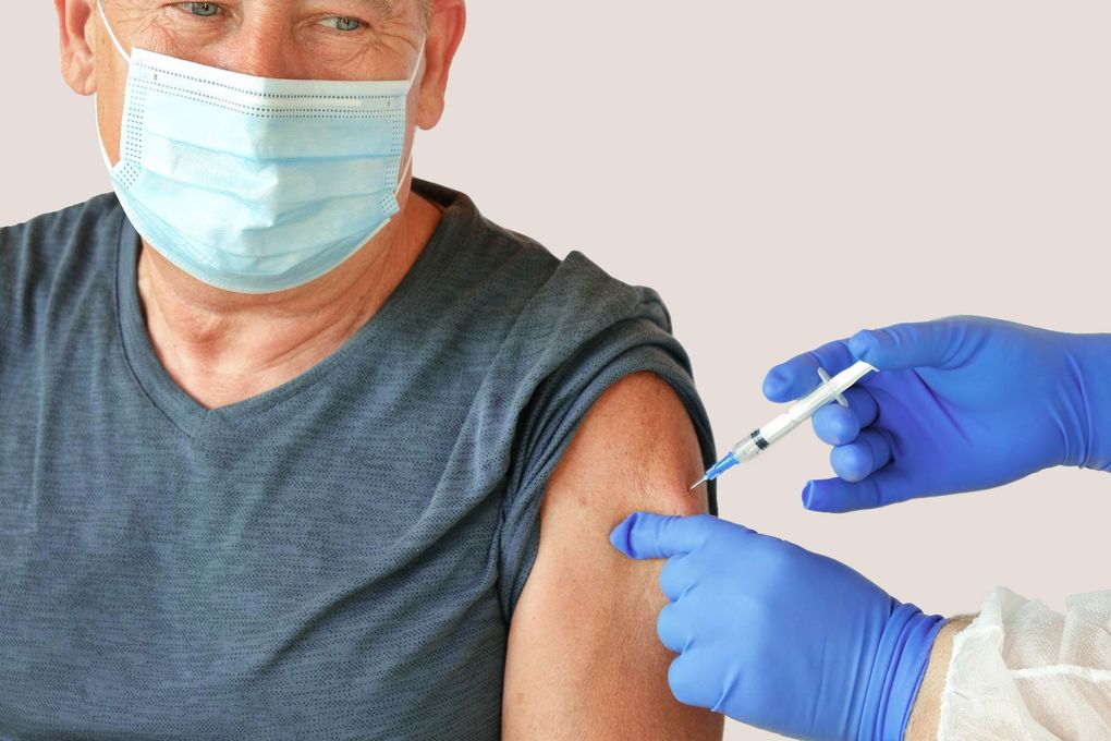 Ein Mann mit einer Maske bekommt eine Impfung in den Arm.