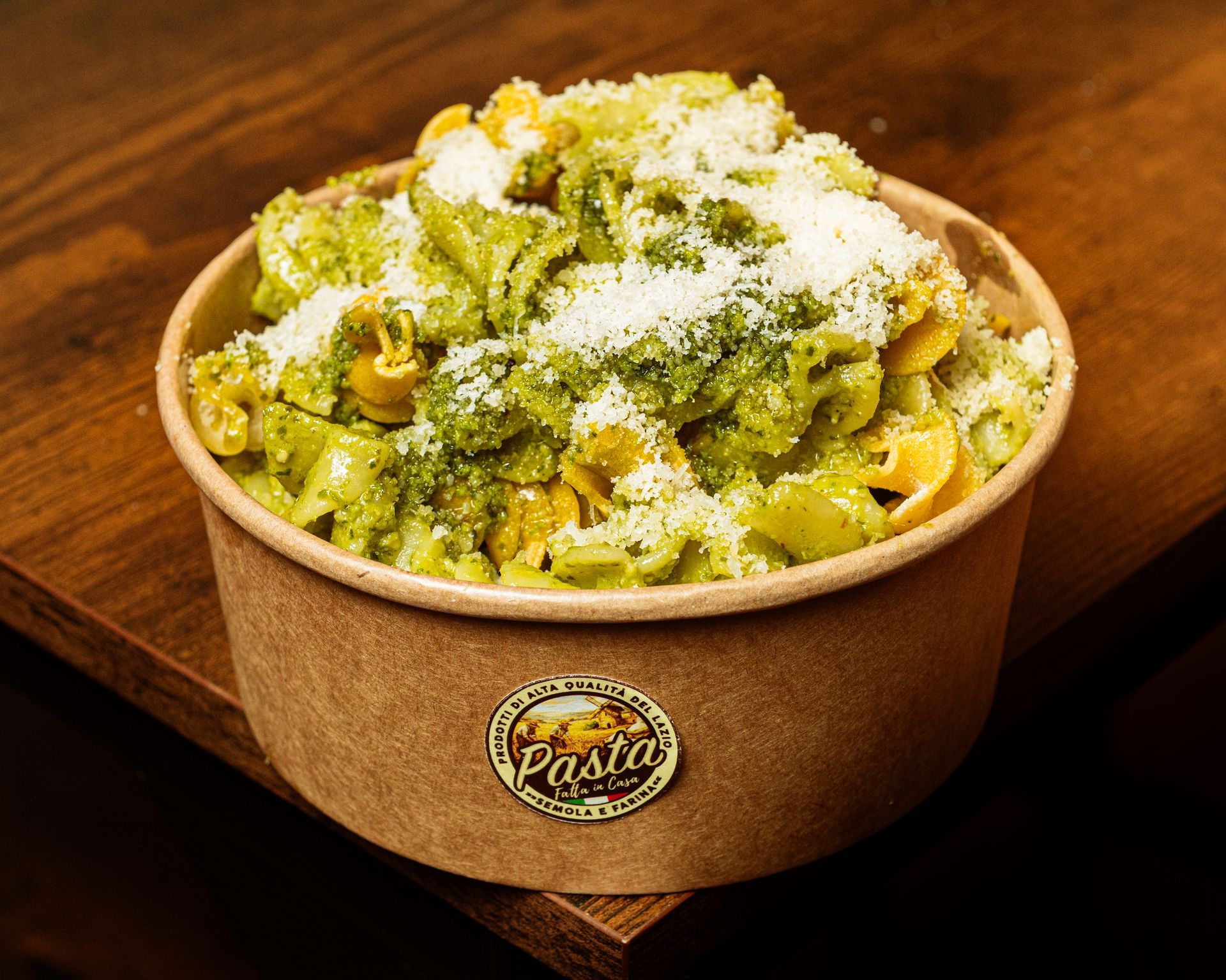 Piatto di pasta al pesto verde su un tavolo rustico, guarnito con foglie di basilico.