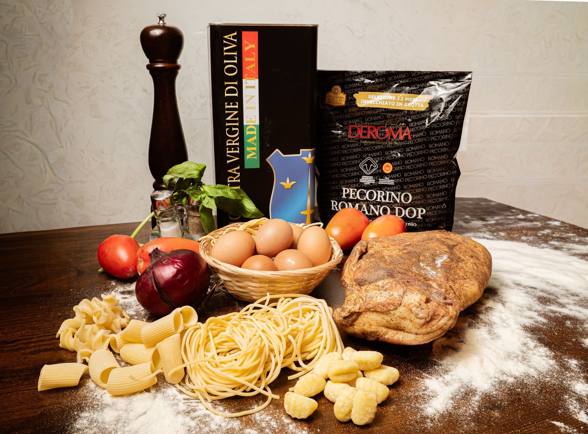 Ingredienti per la pasta con uova, pomodori, cipolla, farina, pepe, libro di ricette e pane su un tavolo