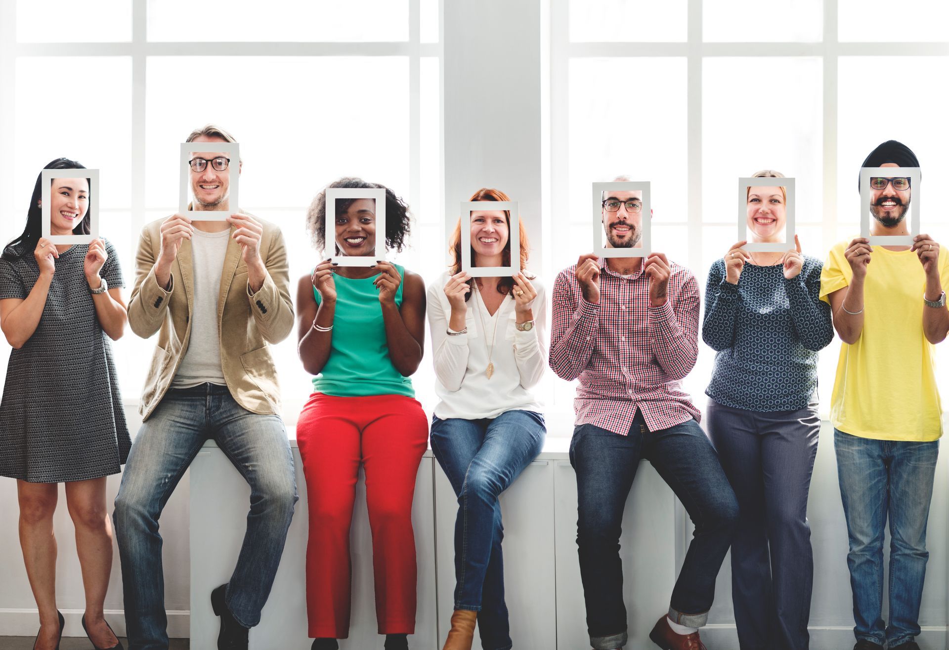 A group of people are holding frames in front of their faces.