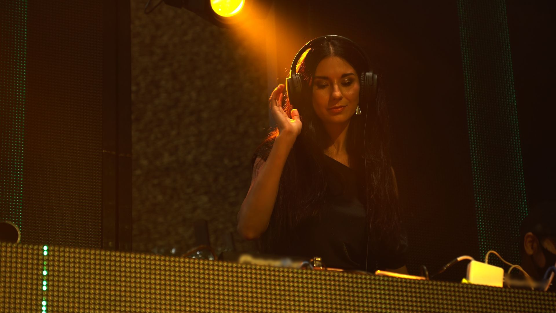 A woman wearing headphones is playing music in a dark room.