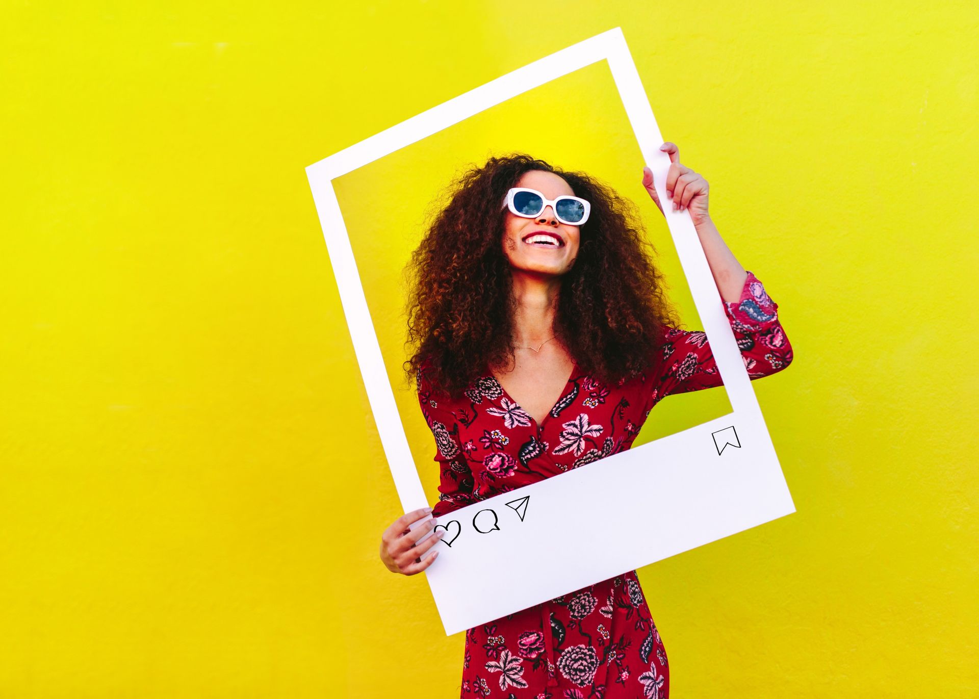 A woman is holding a picture frame in front of her face.