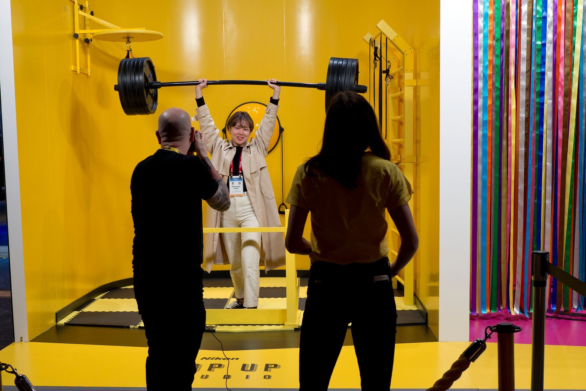 A man is taking a picture of a woman lifting a barbell.