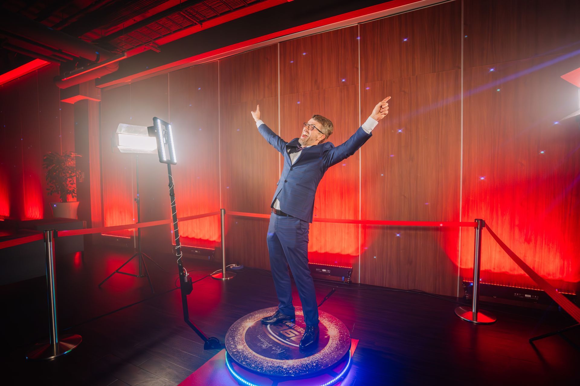 A man in a suit is standing on a 360 degree photo booth.