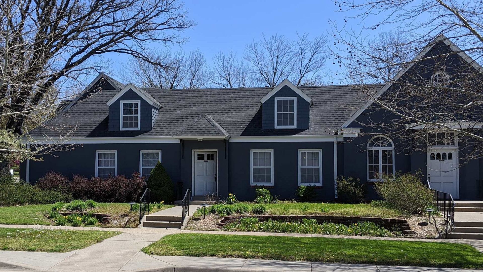 The front door of a house with a porch and plants in front of it.