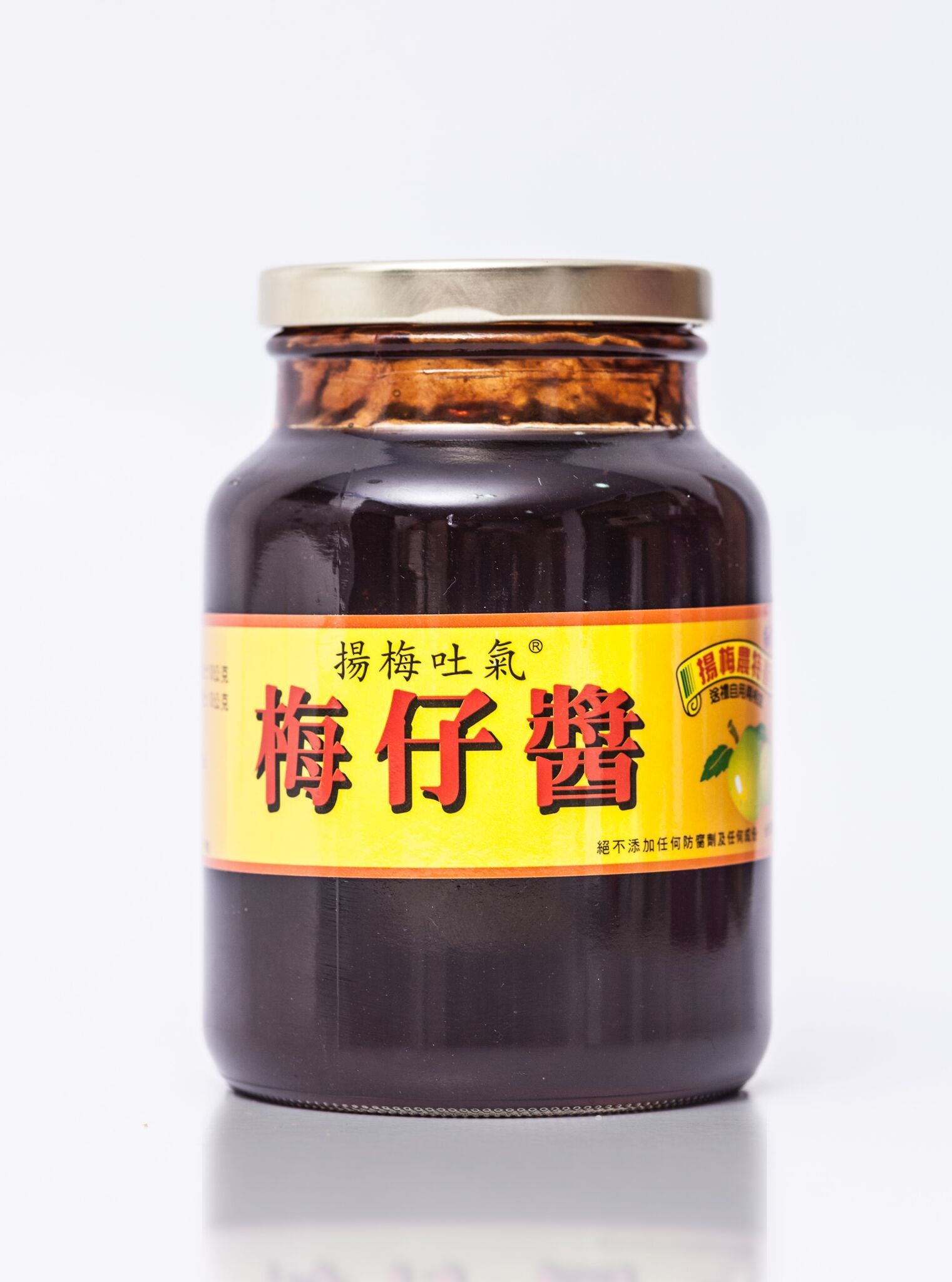 白色背景上的一罐深色李子醬和一小碟醬汁。