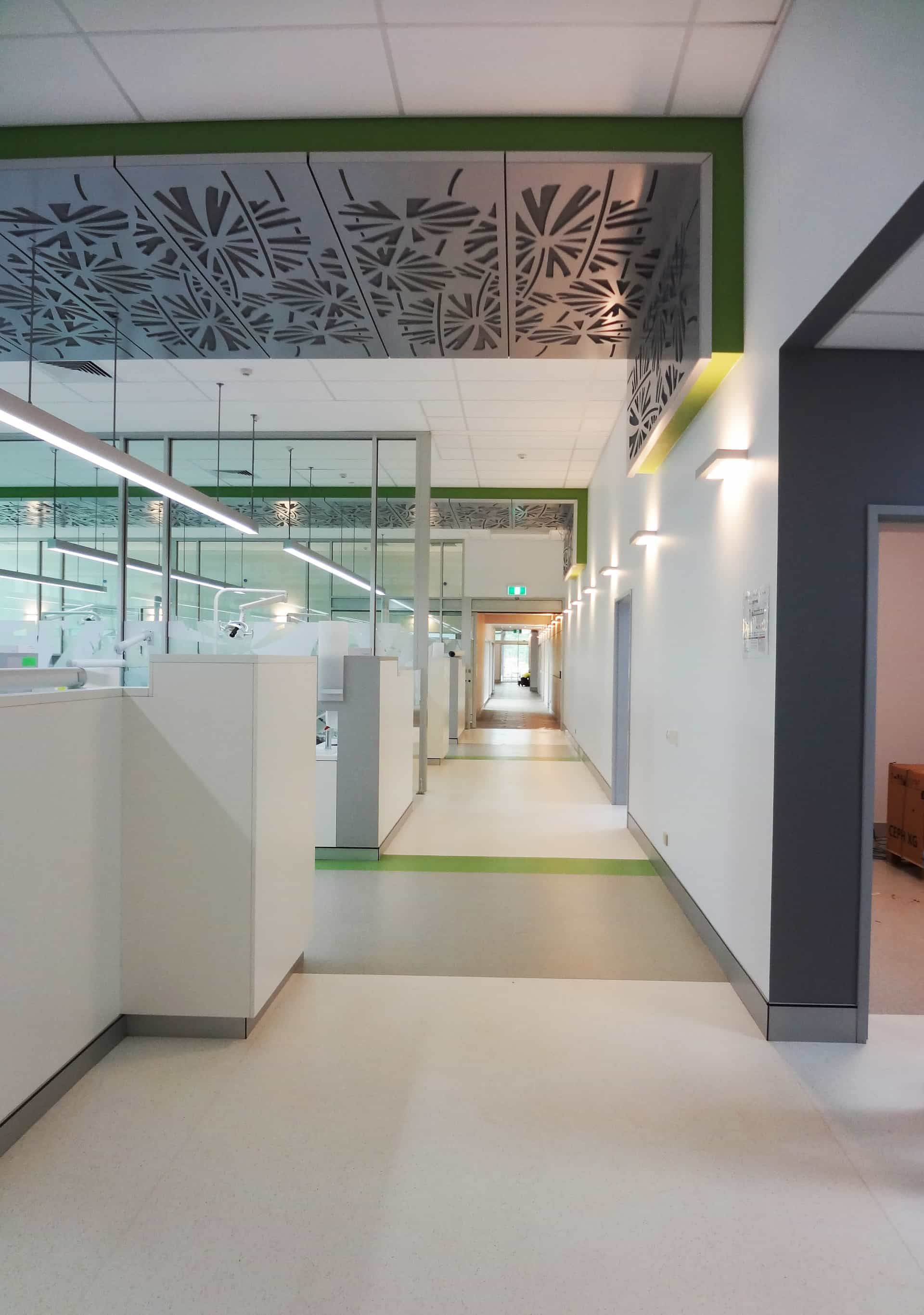 A Long Hallway With White Walls, a Light Gray Floor, and Green Accents Leads to a Distant Doorway — JCU Dental In Smithfield, QLD