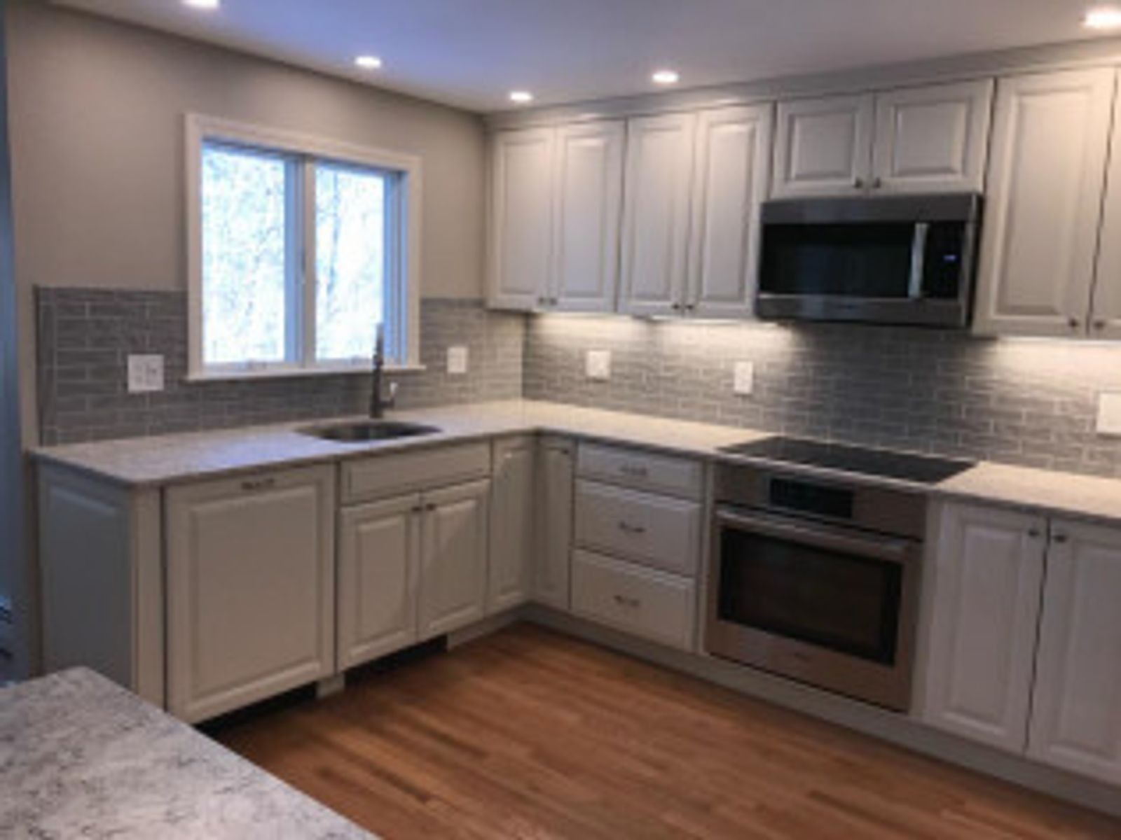 Light gray kitchen with cabinetry, stainless steel appliances, and wood flooring.