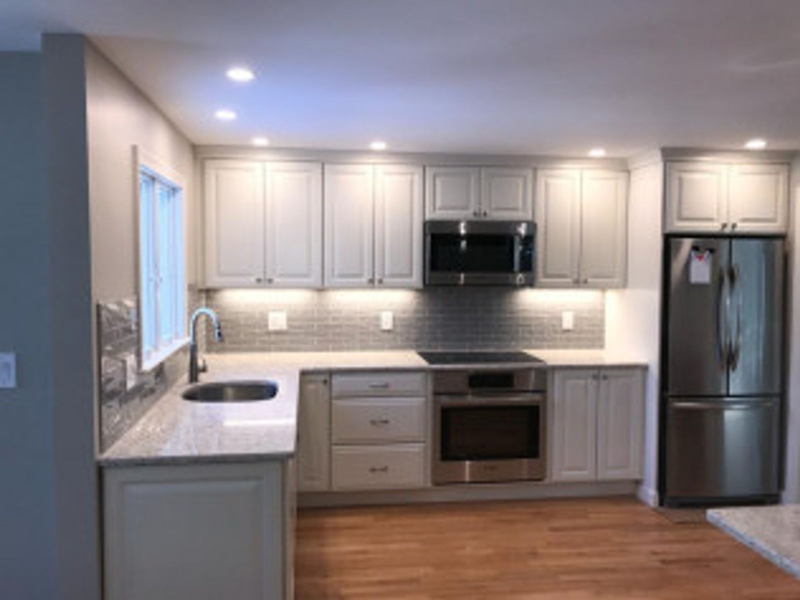Newly remodeled kitchen with gray cabinets, stainless steel appliances, and wood flooring.