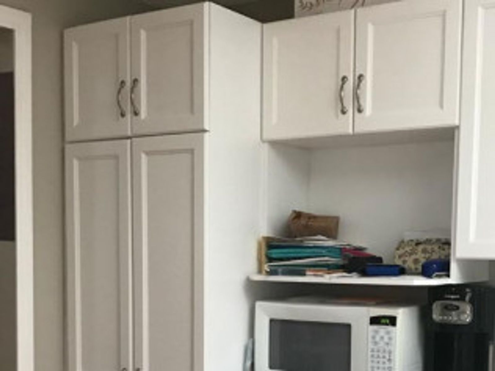 White kitchen cabinets with microwave, shelf, and door.