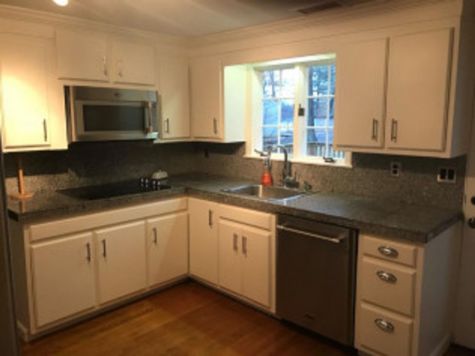 White kitchen cabinets and granite countertops with stainless steel appliances.