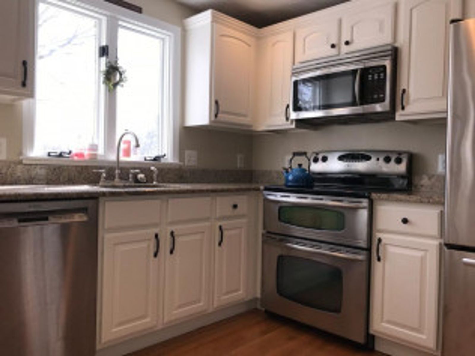 Kitchen with white cabinets, stainless steel appliances, and a window over the sink.