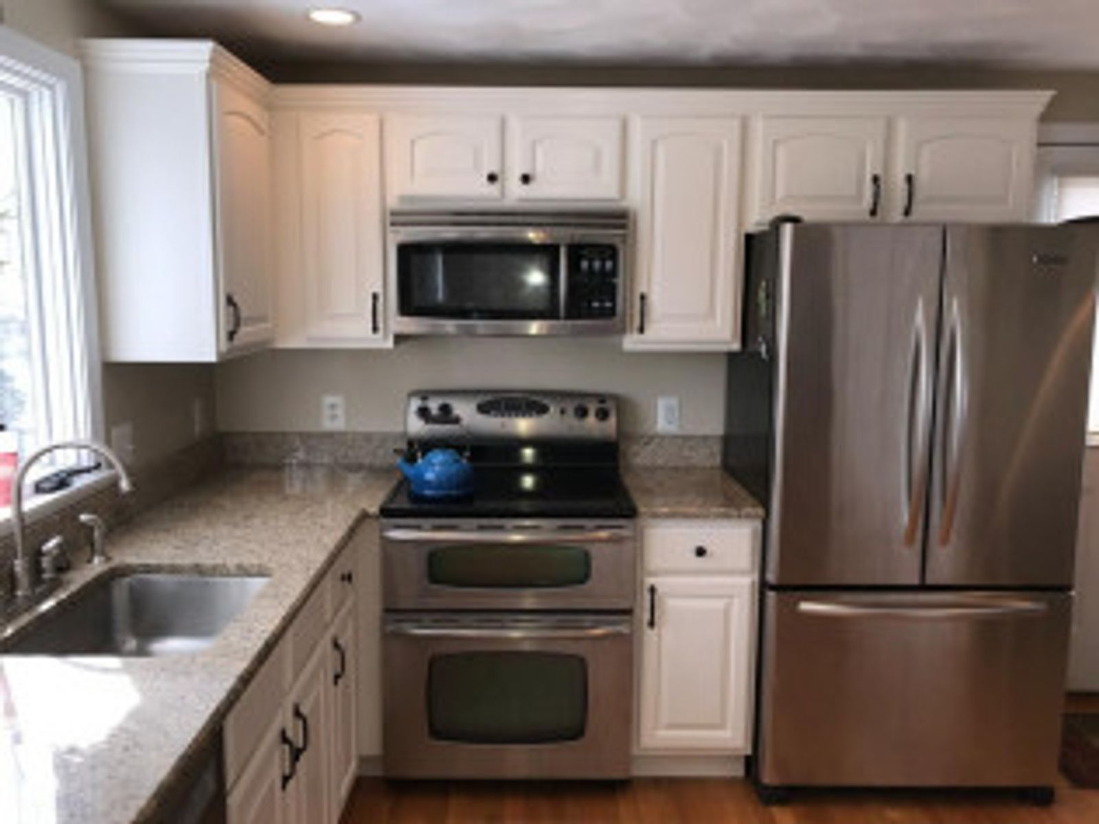 White kitchen with stainless steel appliances, granite countertops, and white cabinets.