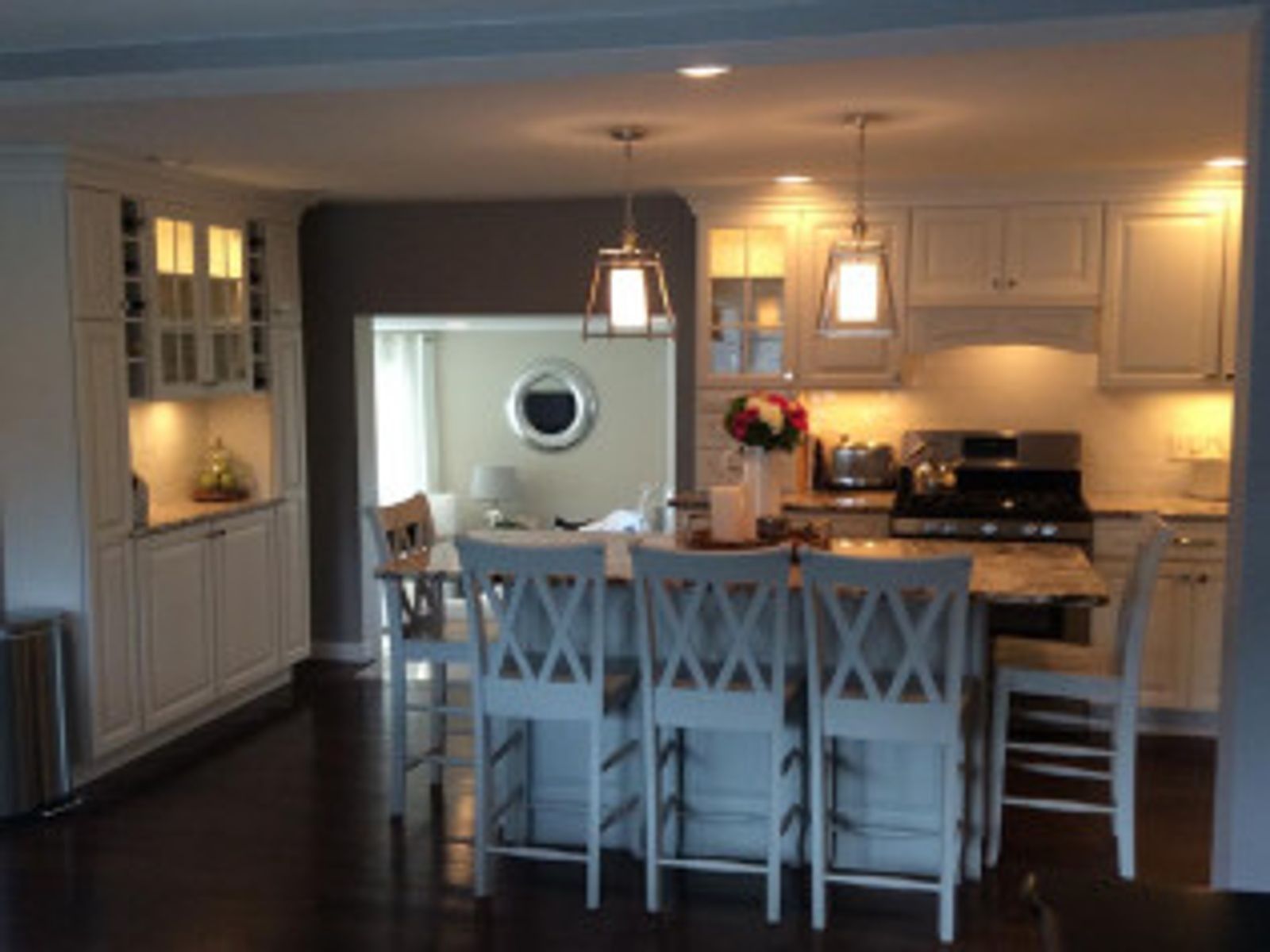 White kitchen with island, bar stools, and doorway to a dining room.