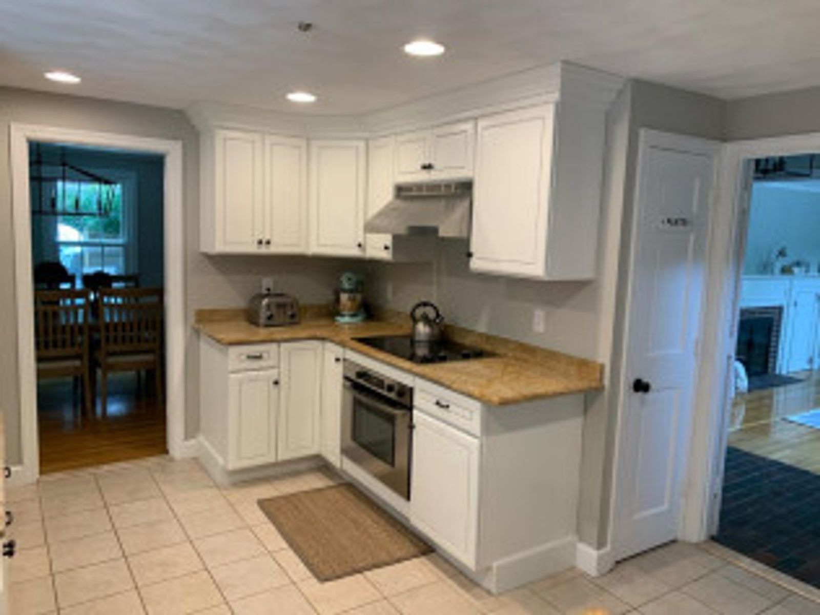 Kitchen with white cabinets, beige countertops, stainless steel appliances, and tile floor.